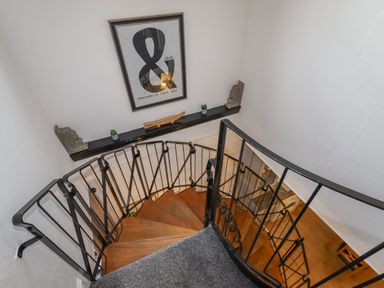 A spiral staircase with black metal railing and wooden steps at The Old Sorting Office in Hawarden