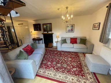 A living room with two sofas a red patterned rug and a spiral staircase at The Old Sorting Office in Hawarden