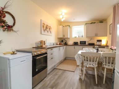 A kitchen with cabinets and table at Sunset Cottage in Swimbridge near Barnstaple