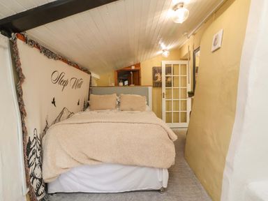 A bedroom with a bed and shelves in Sunset Cottage Swimbridge near Barnstaple