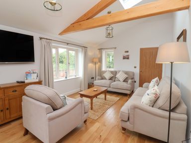 A living room with two sofas a chair coffee table wooden cabinet and large windows at Waverley Cottage in Kilnsea near Easington Hull