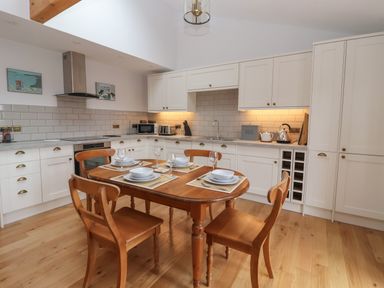 A kitchen with wooden table and chairs set with dishes and glasses at Waverley Cottage in Kilnsea near Easington Hull