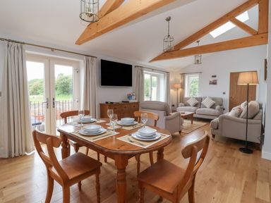An open living and dining room with wooden dining table and chairs and beige sofas at Waverley Cottage Kilnsea near Easington Hull
