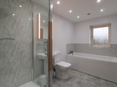 A bathroom with a shower, toilet, sink, bathtub, and a frosted window at Waverley Cottage in Kilnsea near Easington Hull