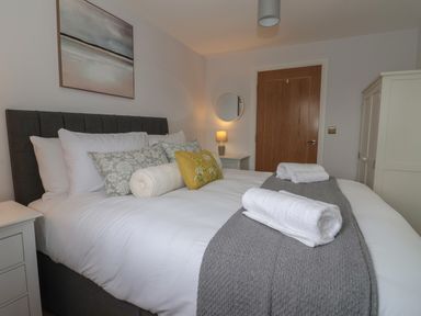 A bedroom with a bed with pillows and towels bedside tables a door a wardrobe and a lamp at Waverley Cottage in Kilnsea near Easington Hull