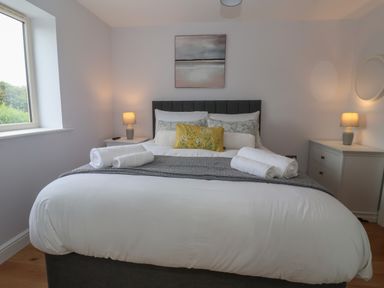 A bedroom with a bed and neatly rolled towels on it lamps on bedside tables and a window at Waverley Cottage in Kilnsea near Easington Hull