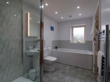 A bathroom with a shower, toilet, sink, bathtub, towel rack, and window at Waverley Cottage Kilnsea near Easington Hull