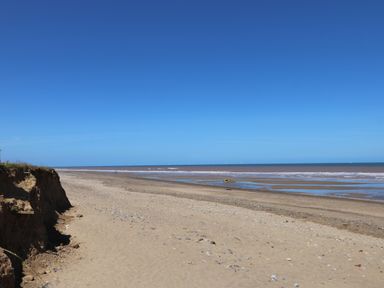 A sandy beach with some rocks and a calm sea under a clear blue sky at Waverley Cottage Kilnsea near Easington Hull
