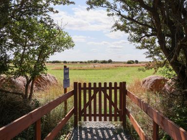 A gate leading to a grassy field at Waverley Cottage in Kilnsea near Easington, Hull