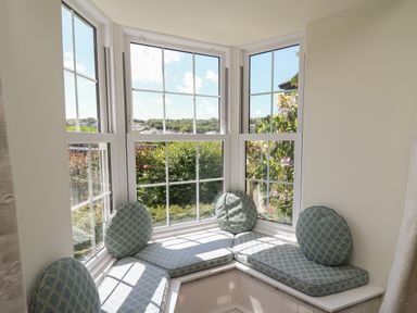A window seat with blue patterned cushions and round pillows in a room at Pen y Graig in Aberporth