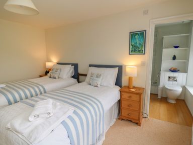 A bedroom with two single beds with striped blankets and a wooden bedside table with a lamp at Pen y Graig in Aberporth