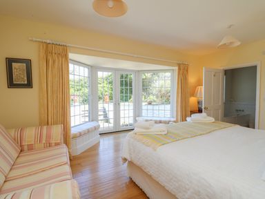 A bedroom with a bed and striped sofa near glass doors leading outside at Pen y Graig in Aberporth