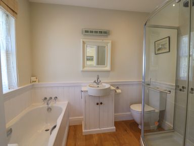 A bathroom with a bathtub a sink with cabinet a toilet and a glass shower enclosure at Pen y Graig in Aberporth