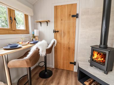 A small dining area with two chairs at a counter by a window and a wood burning stove in a corner at Cariad Mawr in Gwaenysgor near Prestatyn