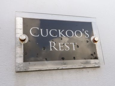 A sign with the text Cuckoo's Rest mounted on a white wall at Cuckoo's Rest in Penryn
