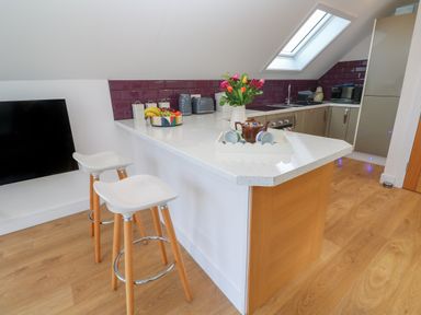 A kitchen with a white countertop island and two white stools at Cuckoo's Rest in Penryn