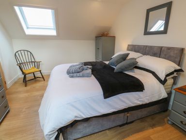 A bedroom with a bed with pillows towels and blanket a wooden chair under a skylight and a wardrobe at Cuckoo's Rest in Penryn
