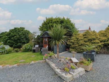 A garden area with gravel and stone planters a small building with chairs and plants at Cuckoo's Rest Penryn