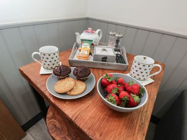 A table with cups, cookies, brownies, and strawberries at Squirrels Lodge in South Molton