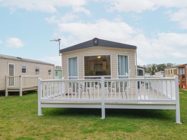 A mobile home with a white railing deck and chairs on grass at No 3 Foxburrow Hang in Belton