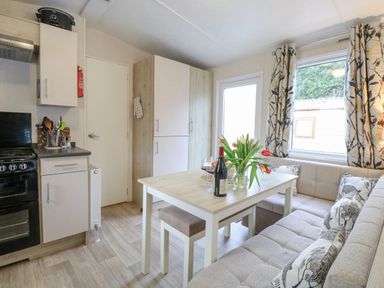A kitchen area with a dining table and cushioned seating with tulips on the table at No 3 Foxburrow Hang in Belton