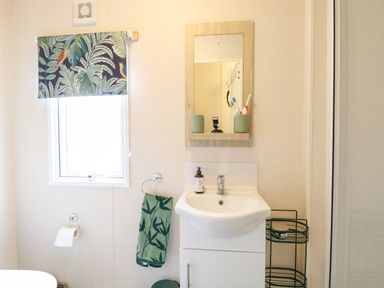 A bathroom with a sink a mirror and a window with a patterned blind at No 3 Foxburrow Hang in Belton