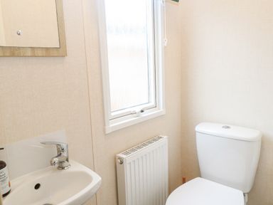 A small bathroom with a toilet a sink a radiator and a frosted window at No 3 Foxburrow Hang in Belton
