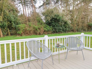 A deck with two chairs and a small table with a coffee press and cup overlooking a grassy area at No 3 Foxburrow Hang in Belton