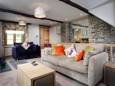 A living room with two sofas and stone wall at The Cosy Peacock in Troutbeck