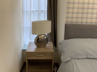 A bedroom with a lamp on a nightstand at Woods Cottage in Usk