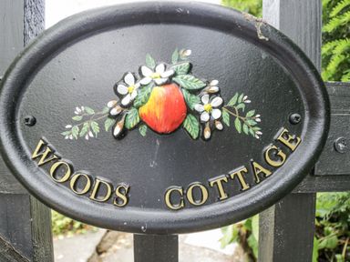 A sign with the text Woods Cottage at Woods Cottage Kingcoed near Raglan