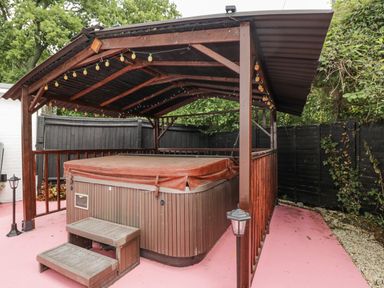 A hot tub under a wooden gazebo in an outdoor area at Woods Cottage near Raglan