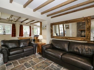 A living room with leather sofas and a mirror at Woods Cottage near Raglan