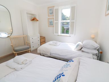 A bedroom with two single beds a wooden chair a tall mirror and a storage unit with hangers at Mariners Watch in Carbis Bay