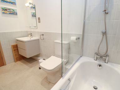 A bathroom with a bathtub shower toilet sink and mirror at Mariners Watch in Carbis Bay