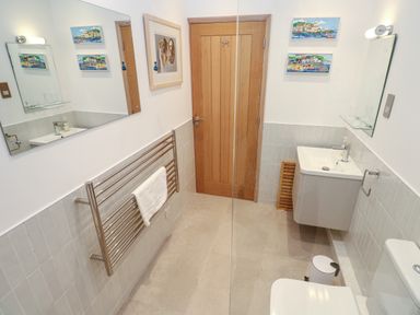A bathroom with a wooden door a towel rack mirrors a sink and a toilet at Mariners Watch in Carbis Bay