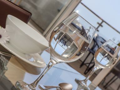 A table with two wine glasses filled with water a white bowl on a plate and a spoon at Mariners Watch in Carbis Bay