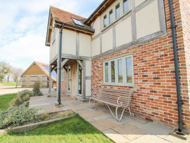 The exterior of a brick and timber house with a bench on the paved patio at Cuckoo Pen Cottage in Eastham near Tenbury Wells