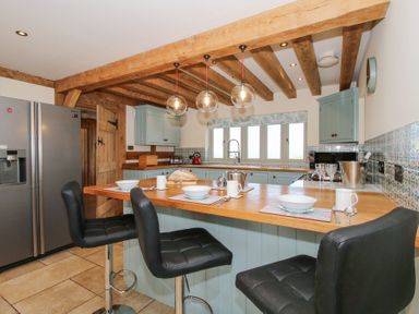 A kitchen with a wooden countertop and black bar stools at Cuckoo Pen Cottage in Eastham near Tenbury Wells