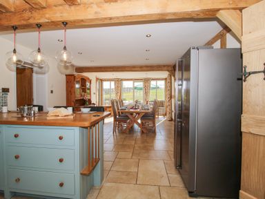 A kitchen with an island and a dining area with a wooden table and chairs at Cuckoo Pen Cottage in Eastham near Tenbury Wells