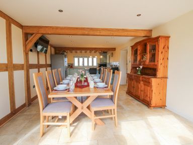 A dining room with a set table and wooden chairs next to a wooden cabinet at Cuckoo Pen Cottage Eastham near Tenbury Wells