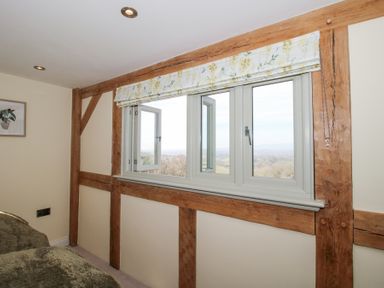 A bedroom window with floral curtain and wooden beams at Cuckoo Pen Cottage Eastham near Tenbury Wells