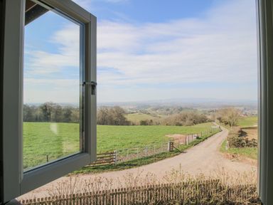 An open window overlooking a country road with green fields and trees at Cuckoo Pen Cottage Eastham near Tenbury Wells