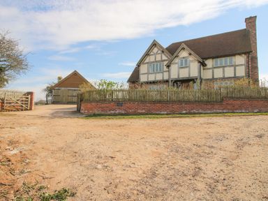 A two-story house with a tiled roof a brick wall and wooden fence in front and a detached garage to the left at Cuckoo Pen Cottage Eastham near Tenbury Wells