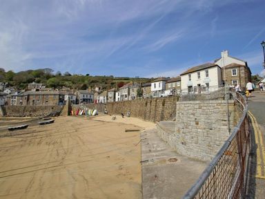 A seaside village with stone buildings and boats on the sand at The Net Loft in Mousehole