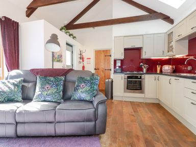 A kitchen and living area with grey sofa and patterned cushions at The Stables in Ruthvoes near St Columb Major
