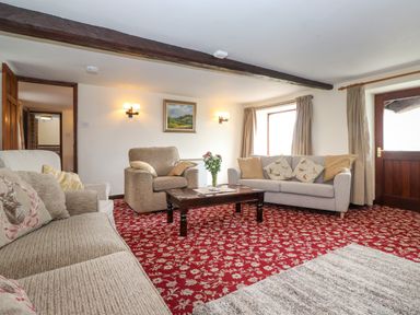 A living room with sofas a coffee table and a painting on the wall at Addyfield Farmhouse in Cartmel Fell near Bowland Bridge