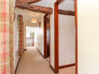 A hallway with wooden beams and plaid curtains at Addyfield Farmhouse Cartmel Fell near Bowland Bridge