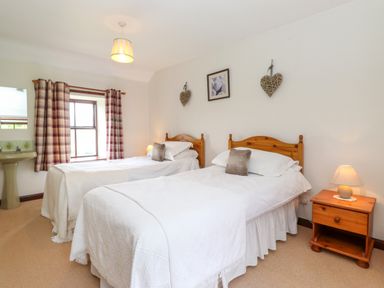A bedroom with two single beds with white bedding and wooden headboards at Addyfield Farmhouse in Cartmel Fell near Bowland Bridge