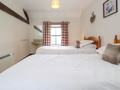 A bedroom with two single beds a window with checkered curtains and a sink at Addyfield Farmhouse Cartmel Fell near Bowland Bridge